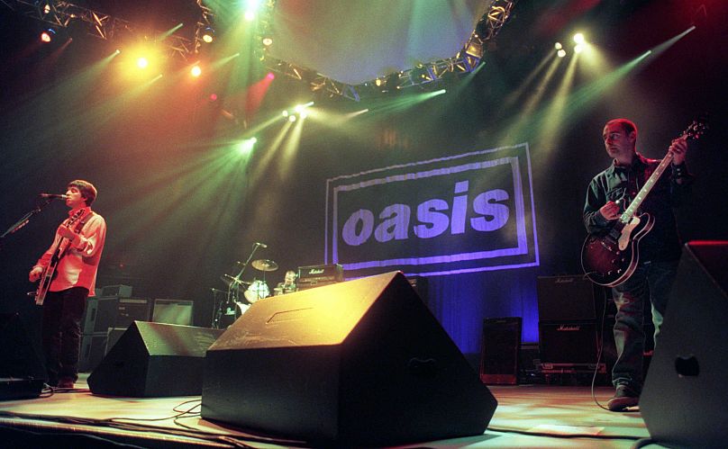 Noel Gallagher, à gauche, Alan White, au centre, et Paul Authurs du groupe Oasis se produisent devant la foule lors de la première du groupe anglais aux États-Unis, en 1996