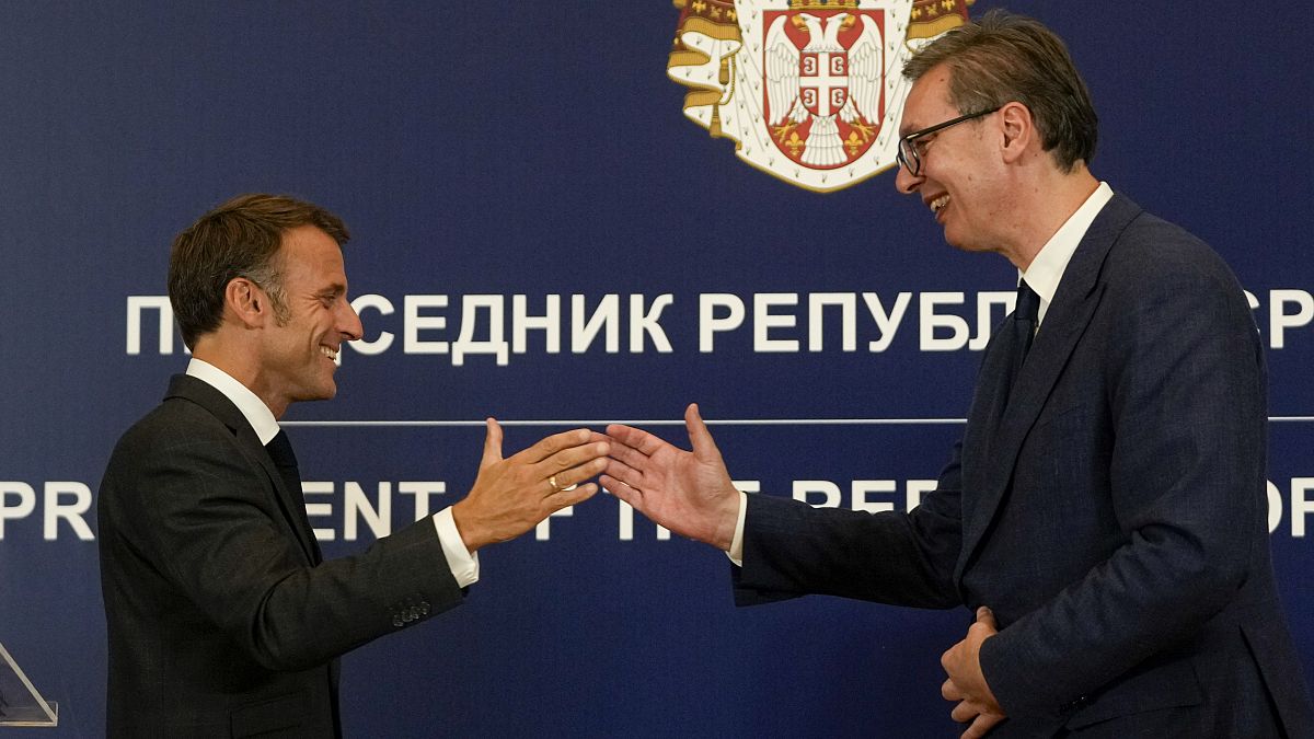 French President Emmanuel Macron clasps hands with Serbian President Aleksandar Vučić after a press conference in Belgrade, August 29, 2024