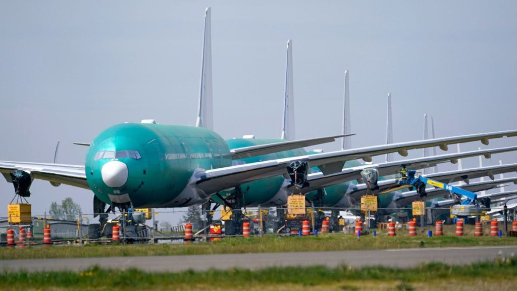 A line of Boeing 777X jets are parked nose to tail on an unused runway at Paine Field, near Boeing