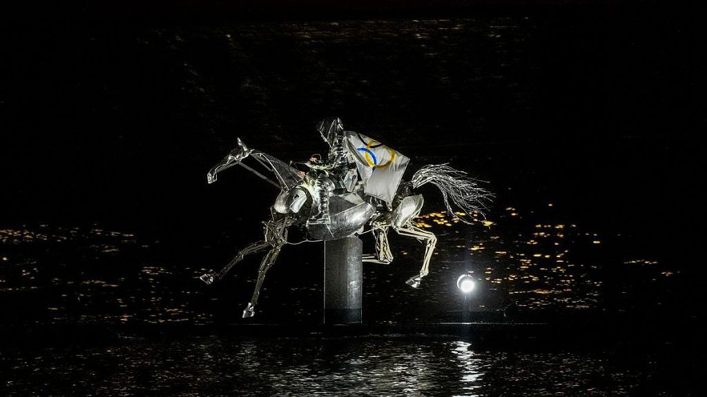 A performer on a mechanical horse carries the Olympic flag down the river Seine in Paris, France, during the opening ceremony of the 2024 Summer Olympics, July 26, 2024.