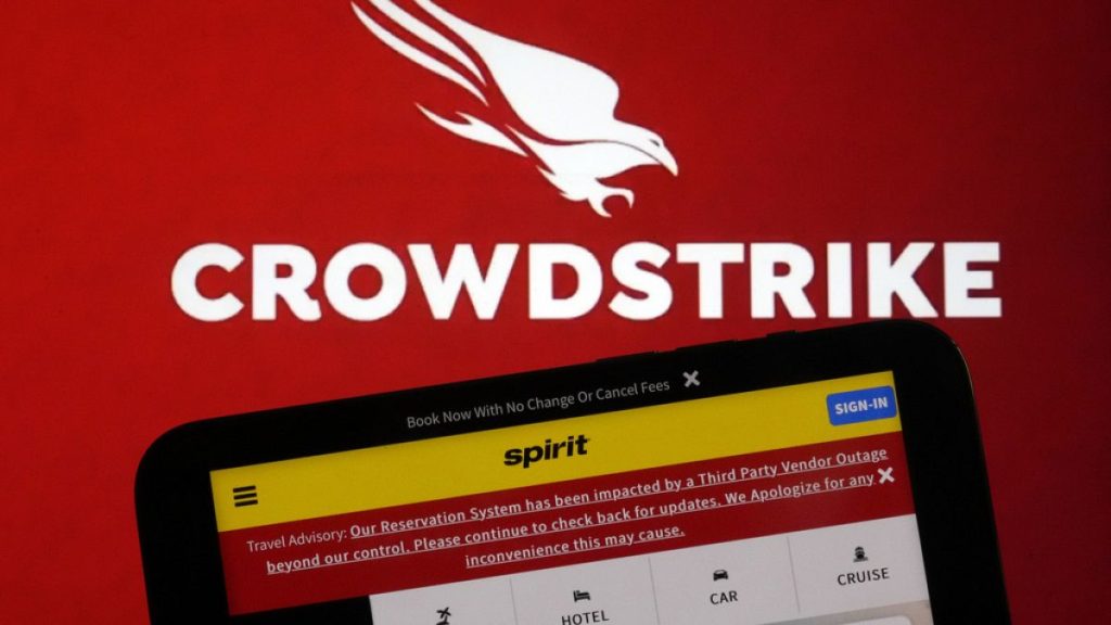 The logo for CrowdStrike and a Spirit Airlines webpage are shown on a computer screen and mobile phone screen, in New York, Friday, July 19, 2024.