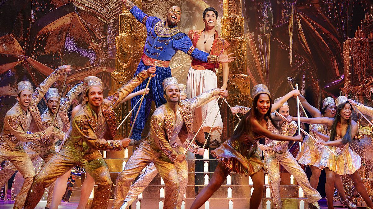 This image released by Disney Theatricals shows Michael James Scott as Genie, and Adi Roy as Aladdin, with the cast during a performance of the musical