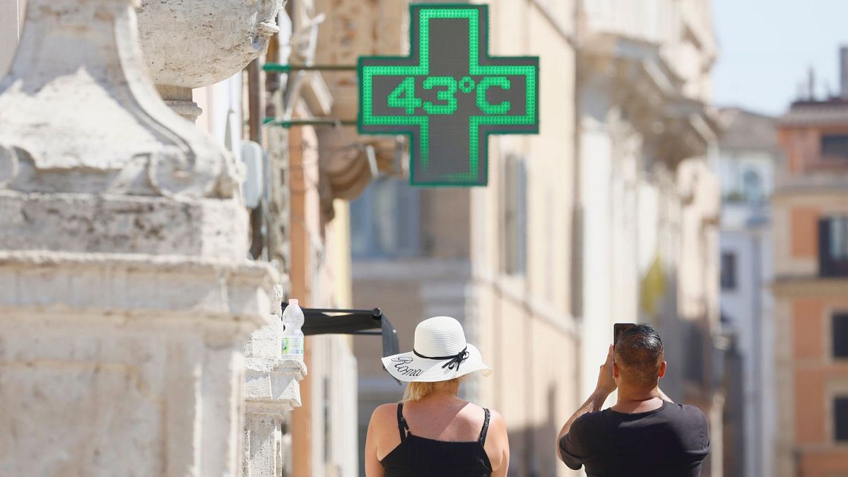 A man takes a photo of the temperature of 43 degrees C recorded in the sun outside a pharmacy in Rome, 11 July 2024.