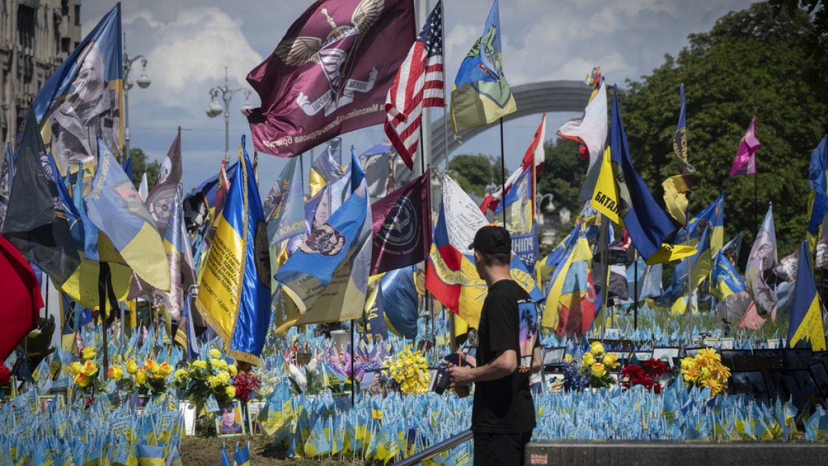 A passer-by looks at a makeshift memorial for fallen Ukrainian soldiers on Independence Square in Kyiv, Ukraine, Tuesday, July 23, 2024.