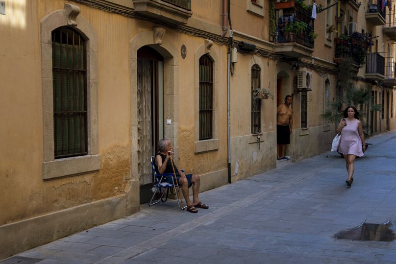 Un homme est assis devant sa maison par une journée chaude et ensoleillée à Barcelone.