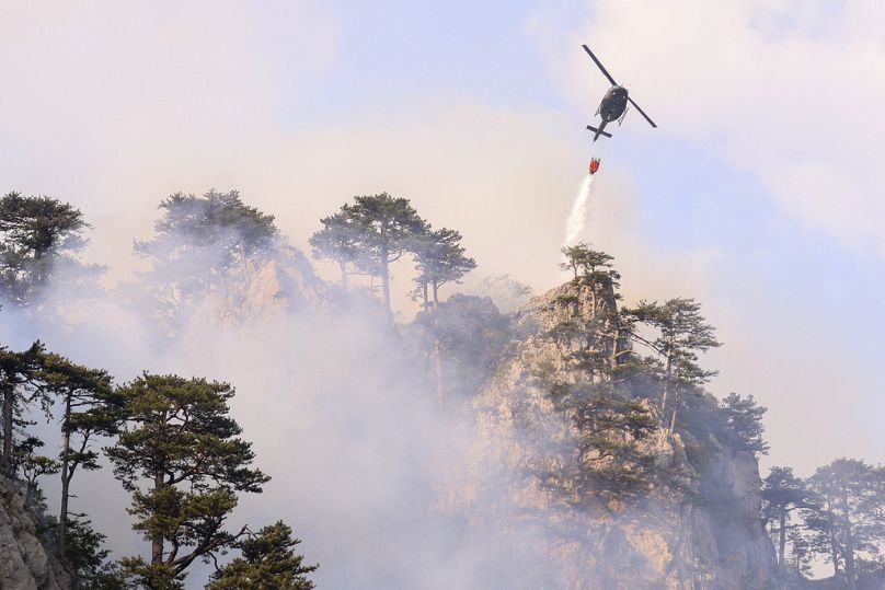 Un hélicoptère largue de l'eau sur un incendie à Tjentiste, en Bosnie, le mardi 13 août 2024. Cinq hélicoptères éteignent un incendie dans le parc national de Sutjeska.