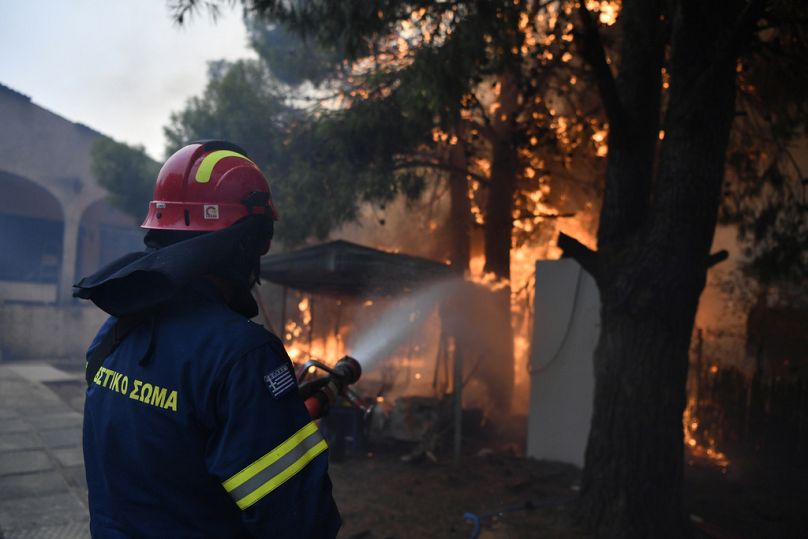 Un pompier s'efforce d'éteindre les flammes d'une maison en feu dans le nord d'Athènes, le lundi 12 août 2024.