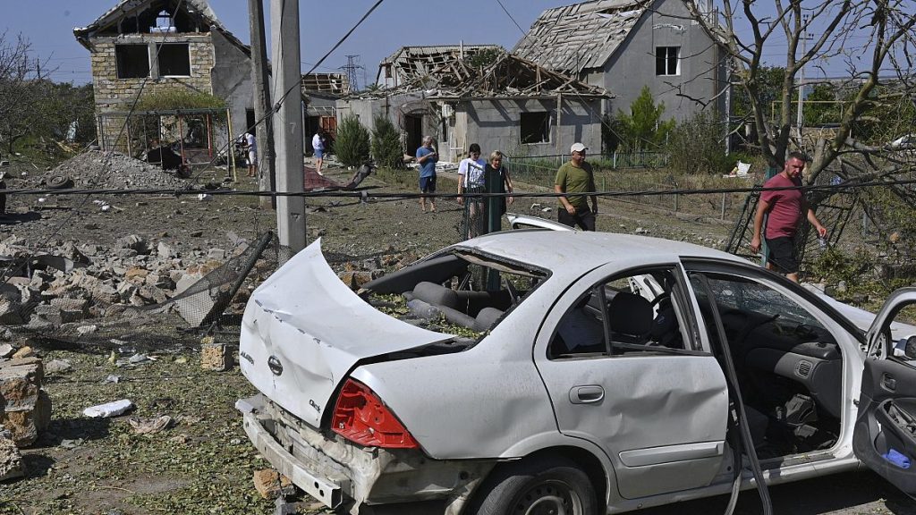 People walk in front of their damaged houses after Russian rocket attack in Usatove village near Odesa, Ukraine, Monday, Aug. 26, 2024. (AP Photo/Michael Shtekel)