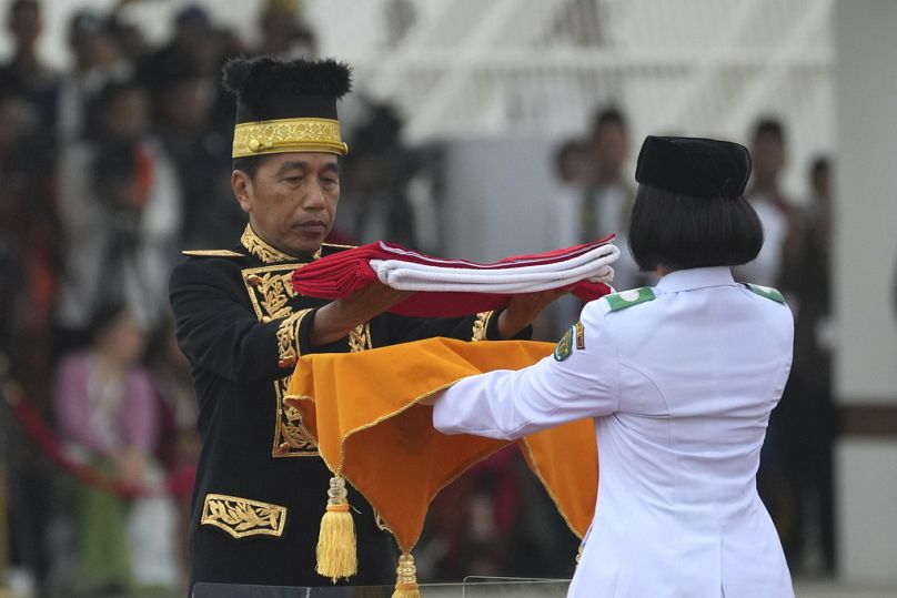 Le président indonésien Joko Widodo, à gauche, remet le drapeau national rouge et blanc à un porteur pour qu'il soit hissé lors de la cérémonie marquant le 79e anniversaire de l'indépendance de l'Indonésie.