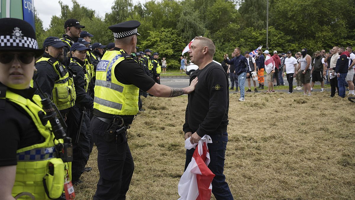 Police officers face protesters outside the Holiday Inn Express in Rotherham, England, Sunday, Aug. 4, 2024.