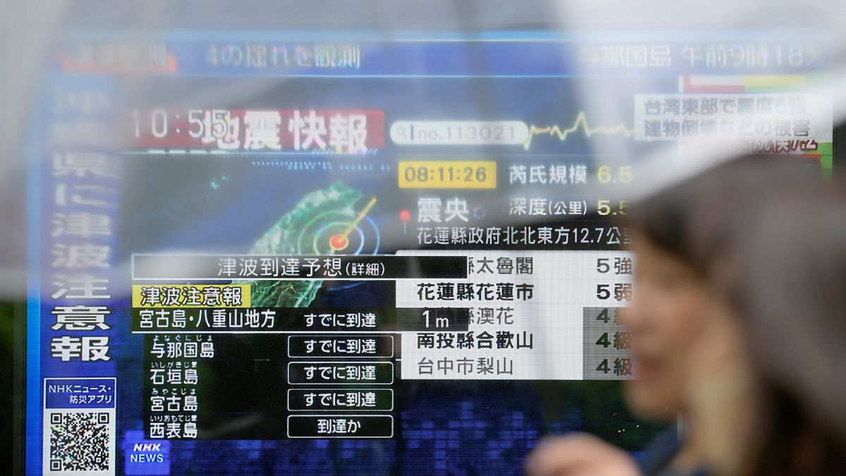 FILE: People walk along a sidewalk by a TV showing a breaking news on tsunami for Okinawa region and Earthquake damage in Taiwan, 3 April 2024