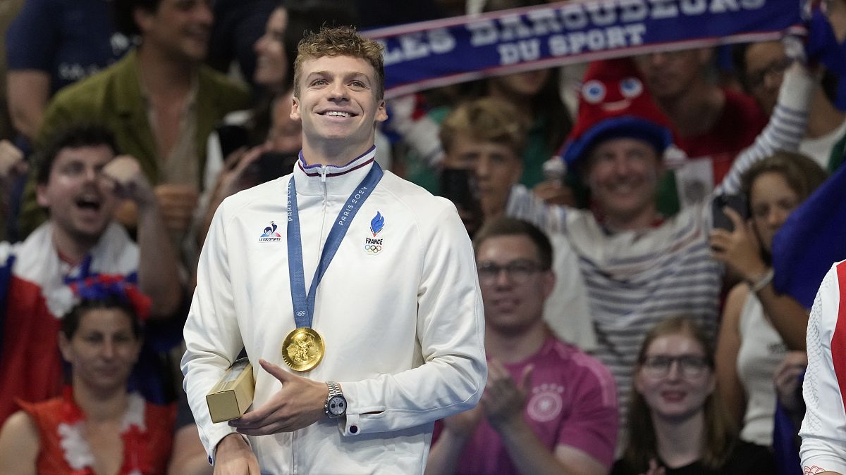 Leon Marchand of France, reacts as he stands on the podium after receiving his gold medal for the men