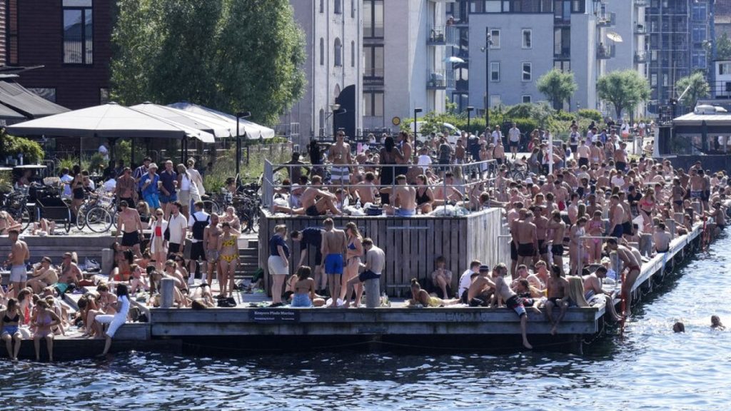 People enjoy sunbathing and refreshment at the harbor in Copenhagen, Denmark, during a hot summer day with temperatures over 30 degrees Celsius, Friday, June 18, 2021.