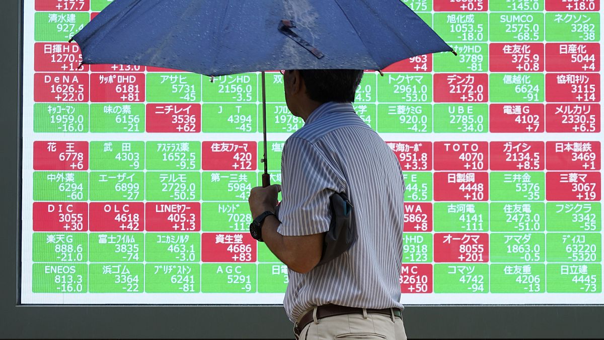 FILE - A person looks at an electronic stock board showing Japan