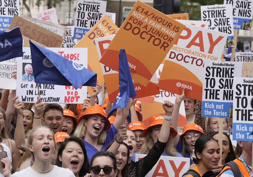 Des manifestants brandissent des banderoles lors d'un rassemblement de jeunes médecins devant Downing Street à Londres, le vendredi 11 août 2023.