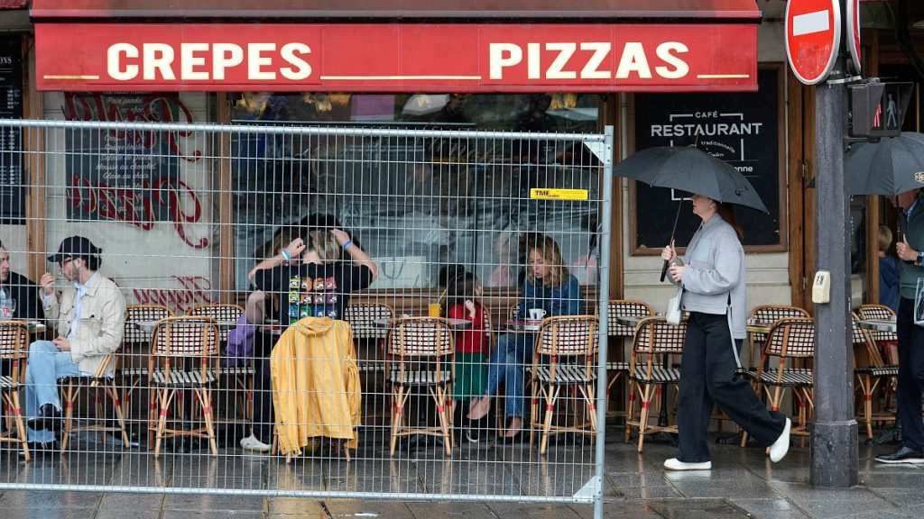 Patrons sit outside a restaurant behind a remaining security barrier on a street along the Seine River, now opened to foot traffic after the Olympic Games