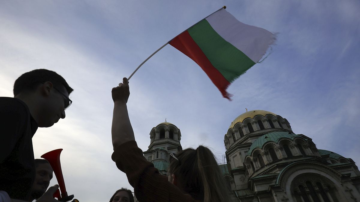 FILE - A pro-government protester holds a Bulgarian flag during a demonstration in support of incumbent Bulgarian government near the Bulgarian Parliament building in Sofia, T