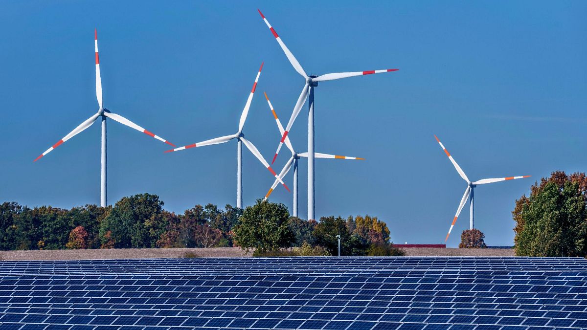 Wind turbines turn behind a solar farm in Rapshagen, Germany, October 2021.