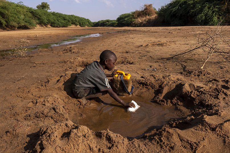 Un jeune garçon recueille le peu d'eau qu'il peut dans une rivière asséchée en raison d'une grave sécheresse en Somalie