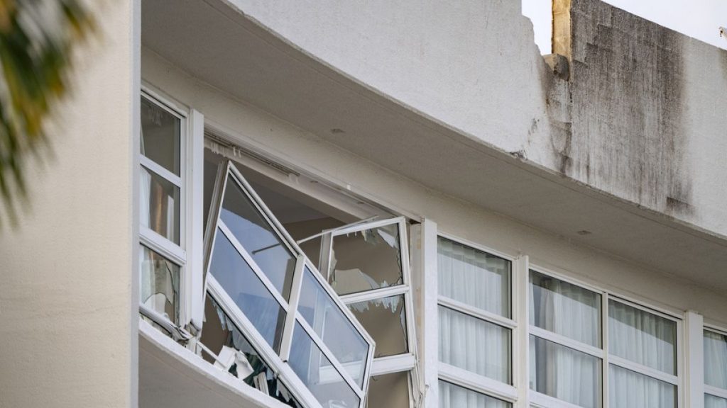 A broken window hands precariously at the Double Tree by Hilton Hotel in Cairns, Australia, after a helicopter crashed into its roof early Monday, Aug. 12, 2024.