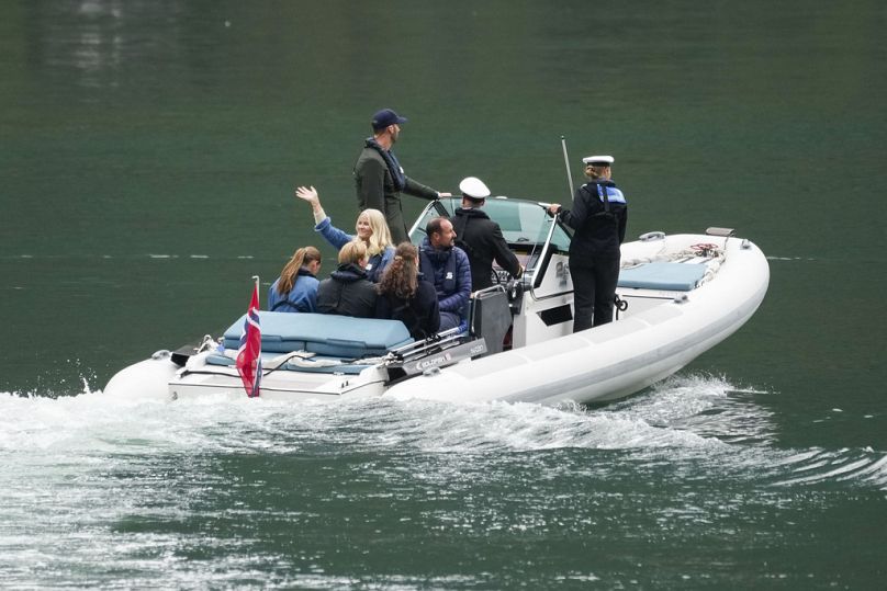 Le prince héritier Haakon de Norvège, 3e à droite, la princesse héritière Mette-Marit, au centre à gauche, saluant la foule, et d'autres membres de la famille royale se rendent à Geiranger, en Norvège, le vendredi 30 août 2024.