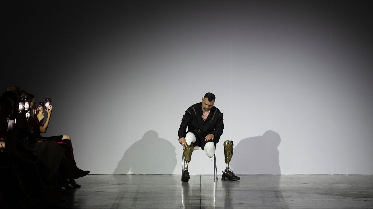 A Ukrainian war veteran puts on his prosthetic to take to the runway to demonstrate outfit by designers Andreas Moskin and Andriy Bilous during Fashion Week show in Ukraine