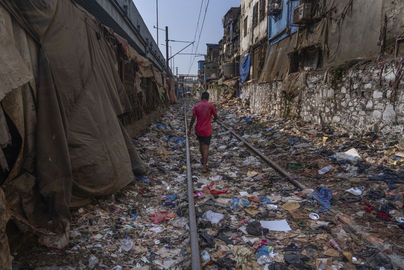 Un homme marche sur une voie ferrée jonchée de plastique et d'autres déchets à Mumbai, en Inde