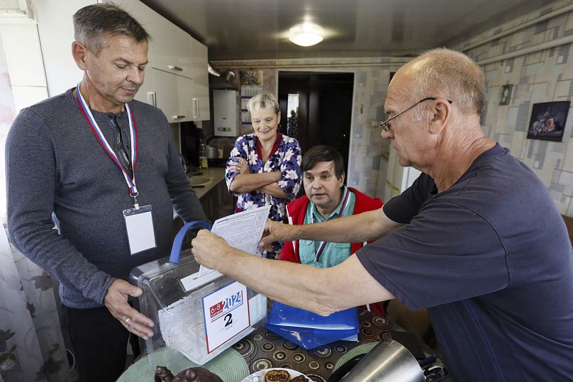 Un homme dépose son bulletin de vote à son domicile tandis qu'un membre d'une commission électorale l'aide à Koursk, le 7 septembre 2024