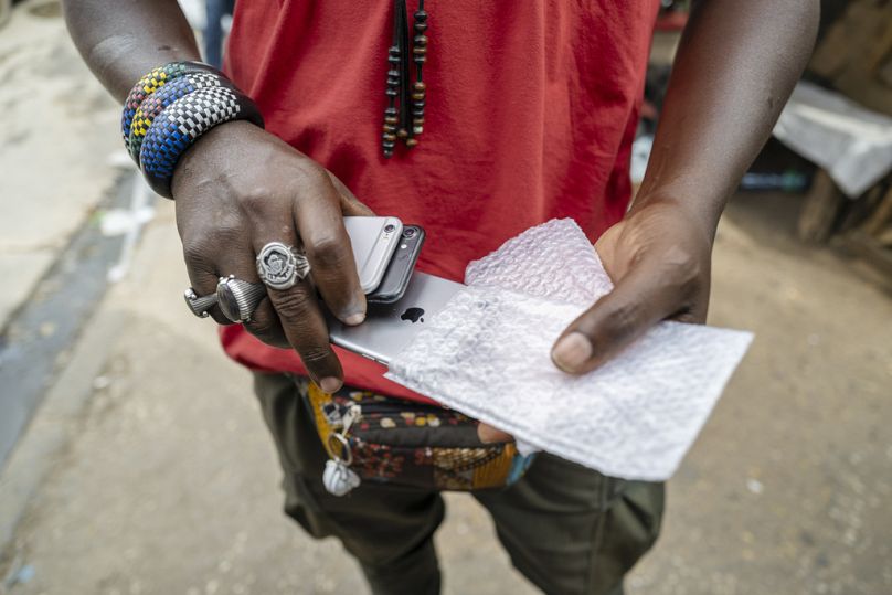 Un homme vend des téléphones portables d'occasion sur le marché de Colobane à Dakar, en février 2024