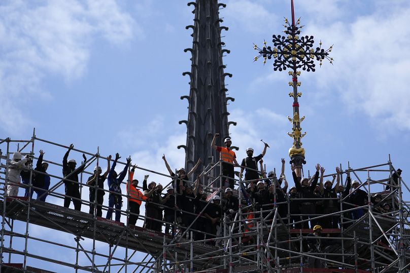 Les ouvriers célèbrent la réinstallation de la Croix du Chevet de la cathédrale Notre-Dame de Paris, à droite, le vendredi 24 mai 2024, à Paris