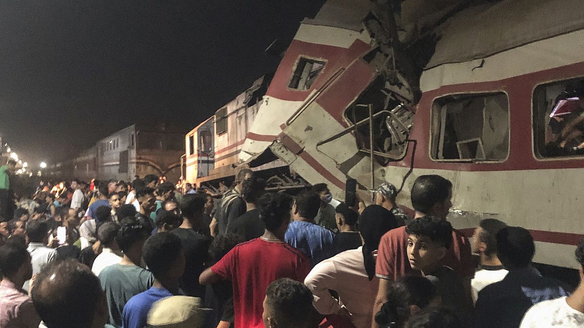 People surround two passenger trains which collided in Egypt