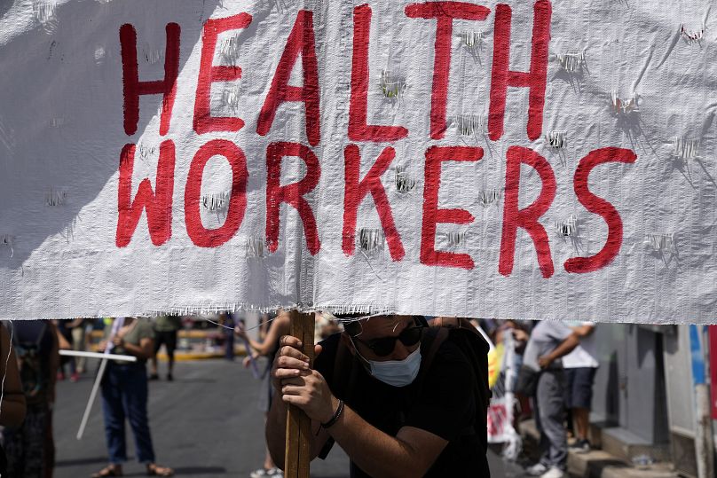 Un partisan des professionnels de la santé tient une banderole lors d'un rassemblement à Athènes, en Grèce.