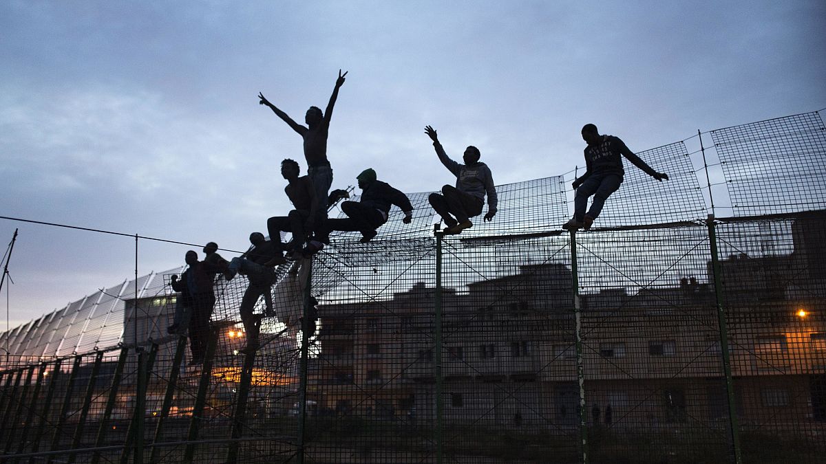 Sub-Saharan migrants climb over a metallic fence that divides Morocco and the Spanish enclave of Melilla, March 29, 2014