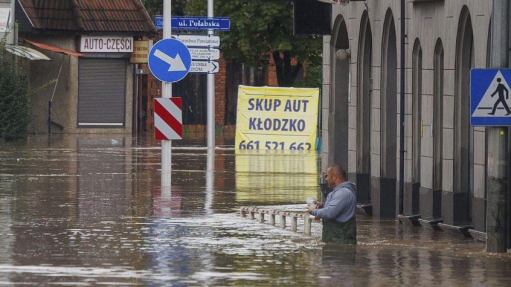 A man stands in waist-deep water that has flooded the streets and houses in the town of Kłodzko, in Poland