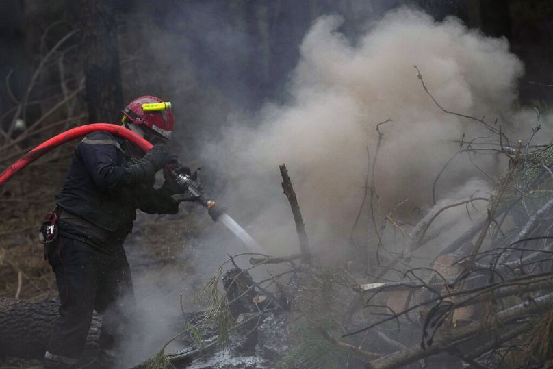 Climat France Un pompier pulvérise de l'eau pour éteindre les restes d'incendies dans une forêt brûlée, à Hostens, au sud de Bordeaux, dans le sud-ouest de la France.