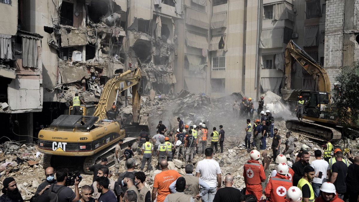 Emergency workers use excavators to clear the rubble at the site of Friday