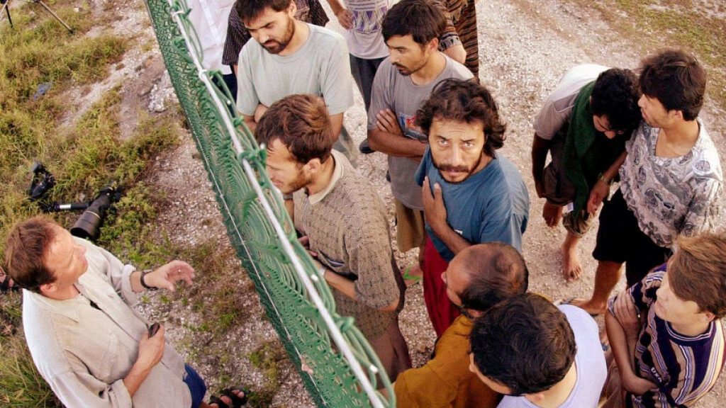 FILE - Refugees gather on one side of a fence to talk with international journalists about their journey that brought them to the Island of Nauru, from 19 September, 2001.