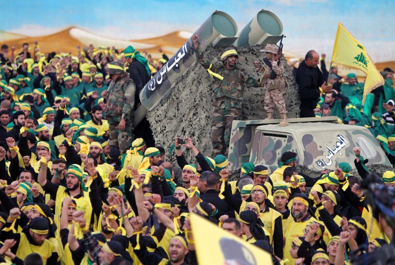 Des combattants du Hezbollah se tiennent au sommet d'un camion équipé de fausses roquettes tandis que leurs partisans scandent des slogans lors d'un rassemblement