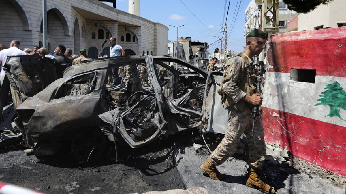 A Lebanese army soldier passes in front a car that was hit by an Israeli strike in the southern port city of Sidon, Lebanon, Wednesday, Aug. 21, 2024. (AP Photo/Mohammad Zaata