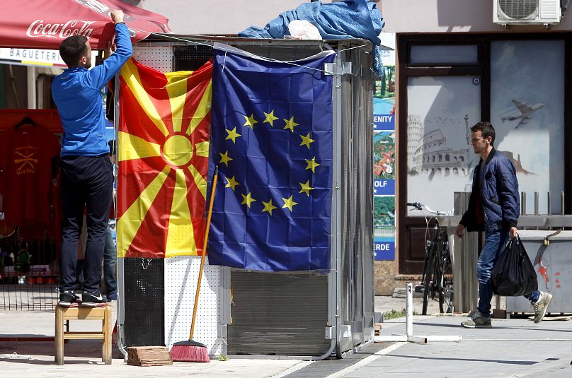 Un vendeur ambulant fixe le drapeau de la Macédoine du Nord à côté d'un drapeau de l'UE dans une rue de Skopje, le 3 mai 2019.