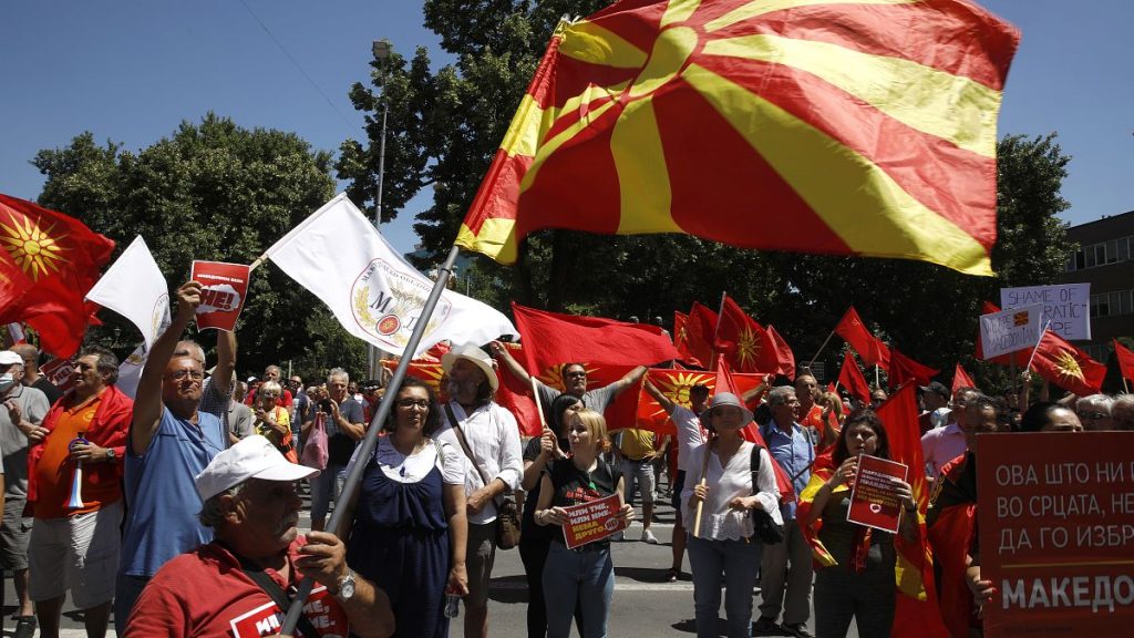 People hold the old and the current national flags and chant slogans during a protest in front of the parliament building in Skopje, July 14, 2022