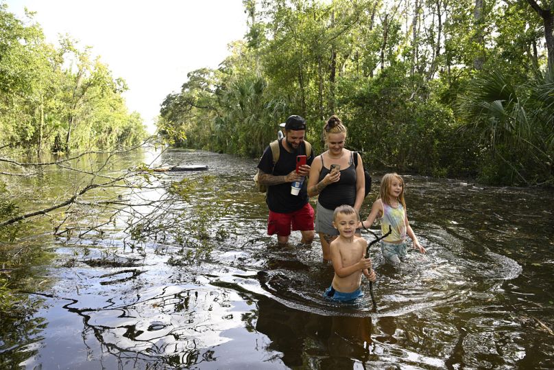 Dustin Holmes, sa petite amie Hailey Morgan et ses enfants Aria Skye Hall, à droite, et Kyle Ross, traversent une route inondée, Crystal River, Floride, le 27 septembre 2024.