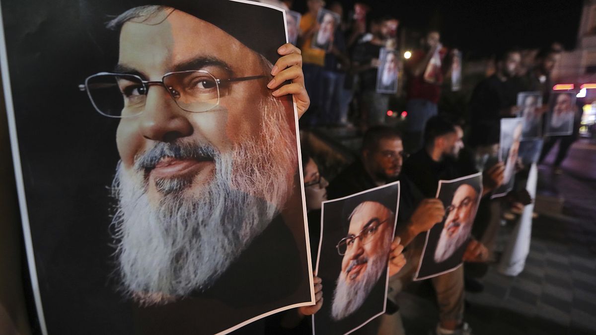 Lebanese and Palestinian men hold portraits of Hezbollah leader Hassan Nasrallah in the southern port city of Sidon, September 28, 2024