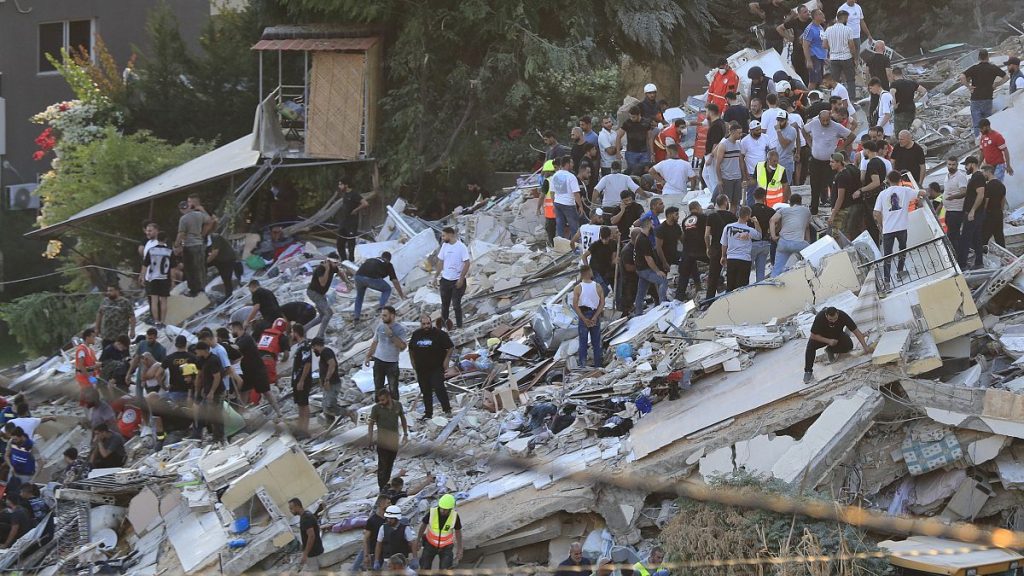 People and rescue workers search for victims after an Israeli airstrike hit two adjacent buildings in the southern port city of Sidon, September 29, 2024