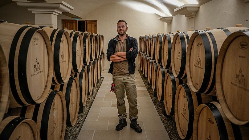 Arnaud Lavantureux, 35 ans, est photographié entre des fûts de vin Chardonnay dans la cave de la propriété, à Chablis, en Bourgogne, France, le 25 septembre 2024. 