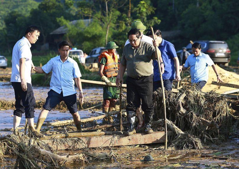 Le Premier ministre vietnamien Pham Minh Chinh, au premier plan à droite, visite le village alors que des opérations de secours sont en cours après qu'une crue soudaine a enseveli un hameau sous la boue et les débris