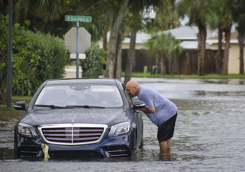 Melvin Juarbe, à droite, tente d'aider un conducteur non identifié dont la voiture a calé dans les eaux de crue causées par l'ouragan Helene le jeudi 26 septembre 2024 à Madeira Beach, en Floride.