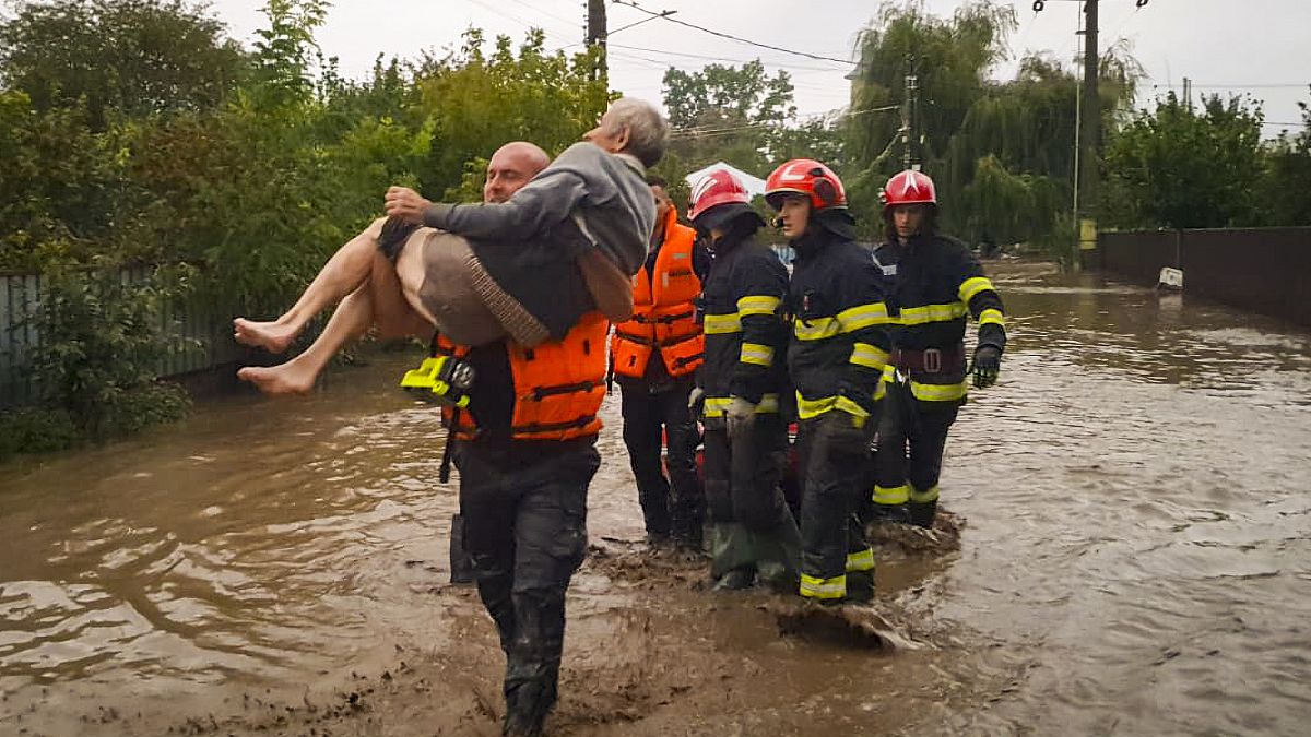 A rescuer carries an old man in Pechea, Romania, Saturday, Sept. 14, 2024 after torrential rainstorms left scores of people stranded in flooded areas.