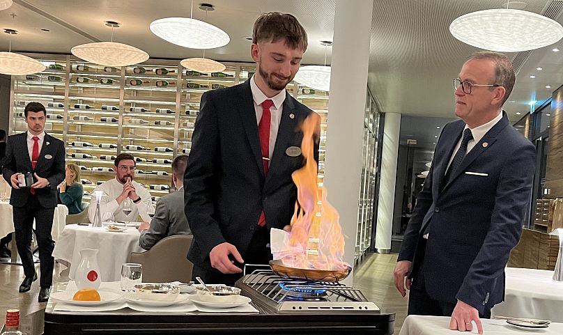 Un étudiant prépare une flambée pour les convives devant ses superviseurs.