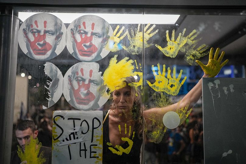 Des manifestants à Tel-Aviv marquent leurs mains sur la fenêtre d'un arrêt de bus avec des photos du Premier ministre israélien Benjamin Netanyahu, le 5 septembre 2024